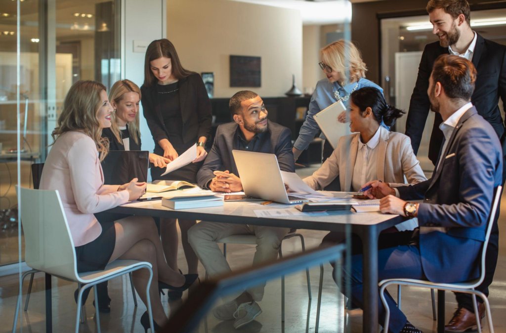 A group of professionals gathered around a conference table discussing documents during a team meeting.